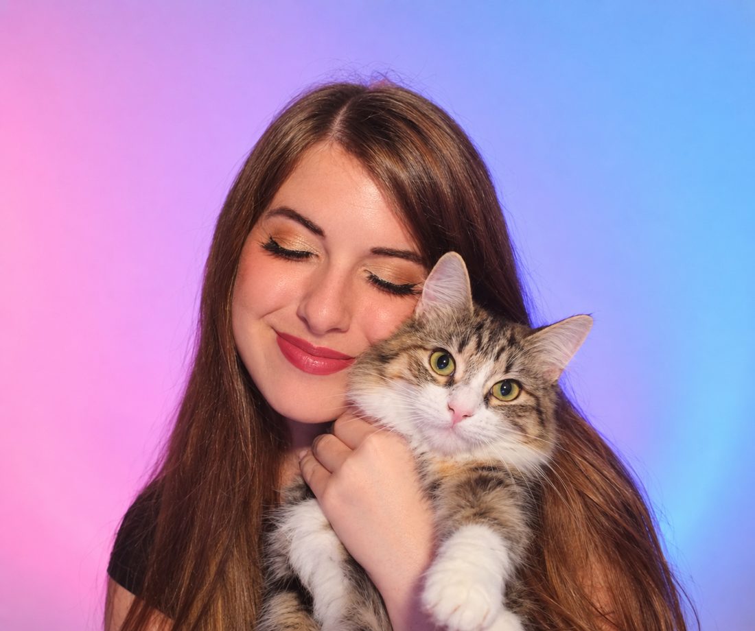 Miranda smiling and snuggling her calico cat